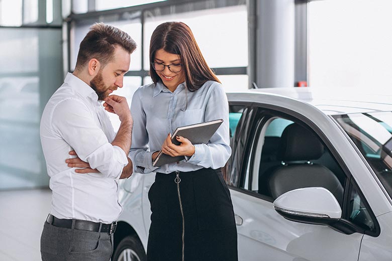 Vendedora de automóveis informando potencial cliente das características do veículo